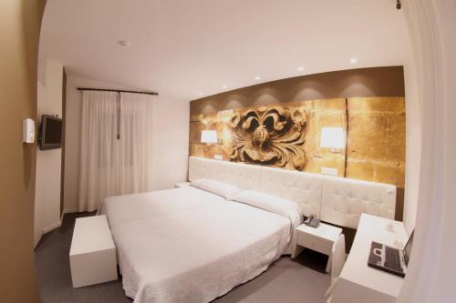 a bedroom with a white bed and a painting on the wall at Hotel Villa Sonsierra in San Vicente de la Sonsierra