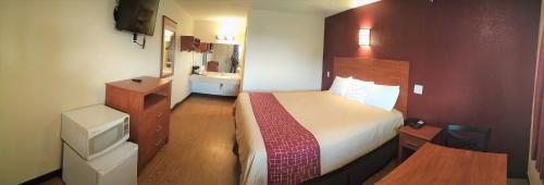 a small hotel room with a bed and a sink at Bastrop Inn in Bastrop