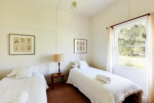 2 camas en una habitación blanca con ventana en Tarndwarncoort Homestead, en Warncoort