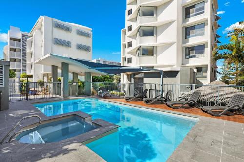 
a hotel room with a swimming pool and a tennis court at Cerulean Apartments in Caloundra
