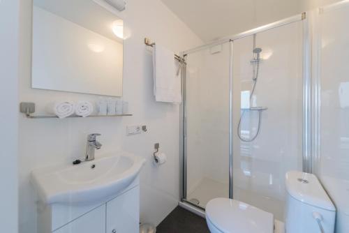 a white bathroom with a sink and a shower at Boatlodge Antigua in Maastricht