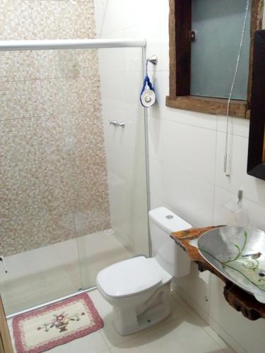 a bathroom with a shower and a toilet and a sink at Pousada Ipoema in Ipoema