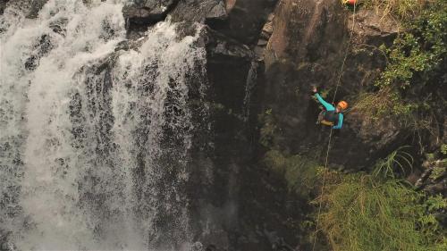 a man is rappelling from a waterfall at The Inn at Kulaniapia Falls in Hilo