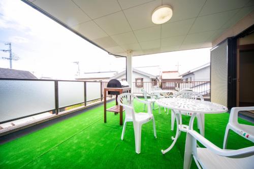 a balcony with white tables and chairs on a green floor at Awaji Seaside Resort in Shiduki1555 in Awaji