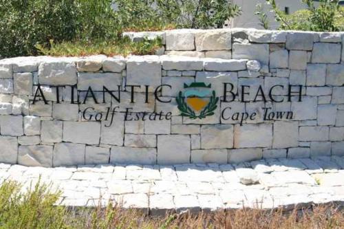 a stone wall with a sign for a turtle beach cape tamarin at The Lodge at Atlantic Beach in Melkbosstrand