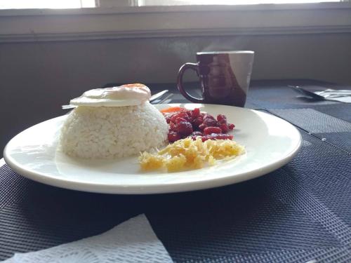 a plate of rice and fruit on a table at Old Orangewood Bed & Breakfast in Baguio