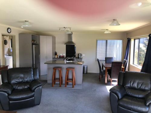 a kitchen and living room with leather chairs and a counter at Lawrence Townhouse Accommodation 16A in Lawrence
