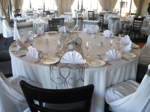 a long table with white tablecloths and napkins at The Lodge at Atlantic Beach in Melkbosstrand