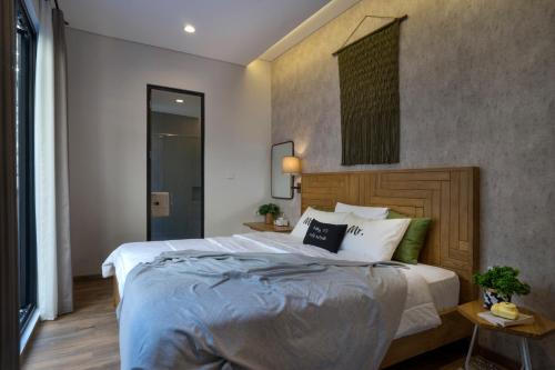 a bedroom with a large bed with a wooden headboard at GAIA Lodge The Kusuma Hill Batu - Malang in Batu