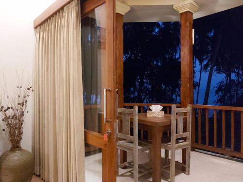 a room with a wooden table and chairs on a balcony at Bahari Villa Tejakula in Tejakula