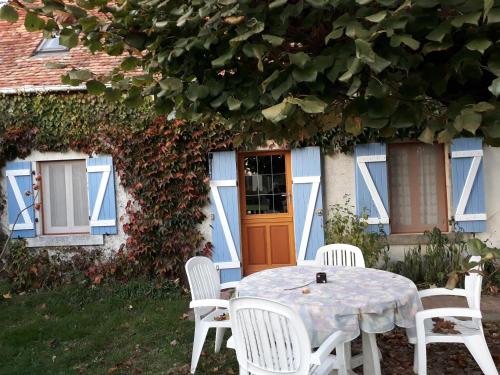 a table and chairs in front of a house at La maison de Xenos in Nohant-en-Graçay