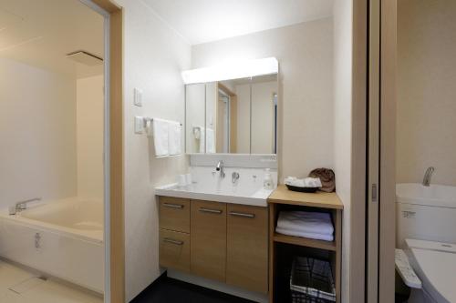 a bathroom with a sink and a tub and a mirror at Hotel REUS Ashoro in Ashoro