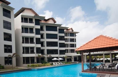 a hotel with a swimming pool in front of a building at Samsuria Exclusive Beach Penthouse in Kampung Sungai Ular