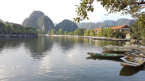 a group of boats sitting on a river with mountains at Lys Homestay in Ninh Binh