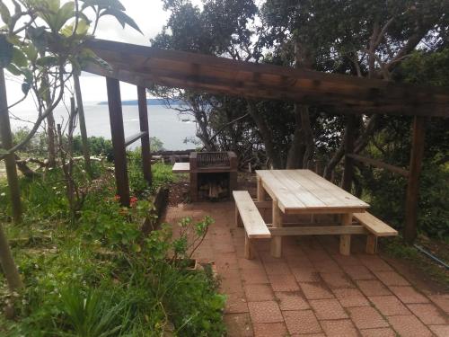 a picnic table and bench under a pergola at Alojha Coliumo Dichato in Coliumo