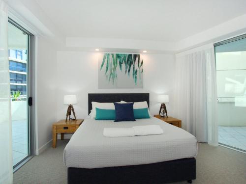 a bedroom with a large bed with blue pillows at Sirocco 201 in Mooloolaba