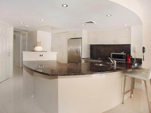 a kitchen with white cabinets and a granite counter top at Zanzibar 404, Sensational 2 Bedroom Oceanview Apartment in Mooloolaba