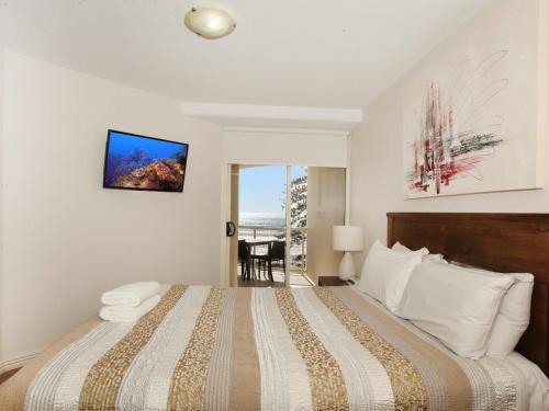a bedroom with a large bed with a television on the wall at Zanzibar 404, Sensational 2 Bedroom Oceanview Apartment in Mooloolaba