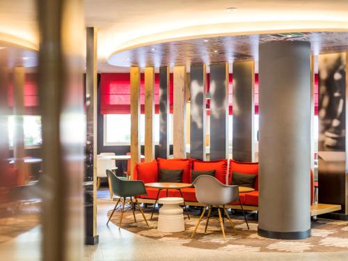 a restaurant with red chairs and a table in a room at Ibis Barcelona Castelldefels in Castelldefels