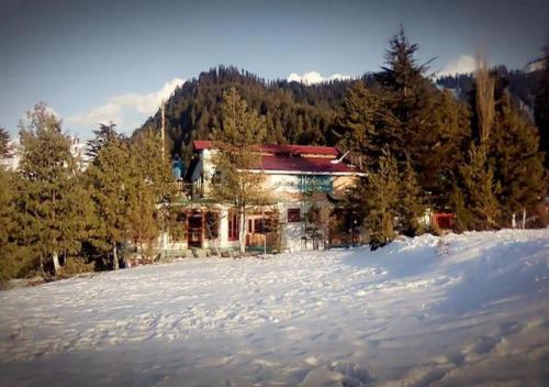 a house on top of a snow covered hill at Tourist Inn Hotel in Shogran