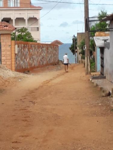 a man walking down a dirt road in a village at Appartement vue sur mer in Toubab Dialaw