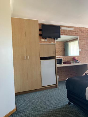 Habitación con cama y armario con TV. en Branxton House Motel en Branxton