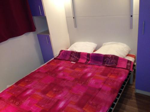 Una cama con una manta rosa encima. en Domaine Plein Sud, en Bruzac