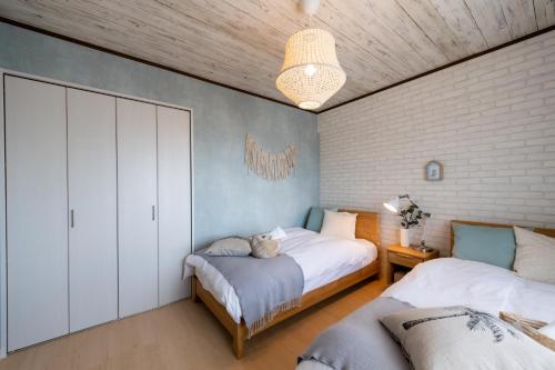 a bedroom with two beds and a wall at Little Santa in Ginowan