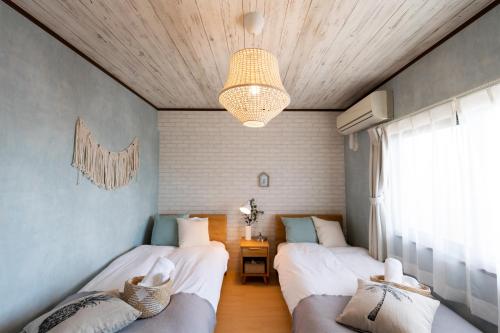 a bedroom with two beds and a chandelier at Little Santa in Ginowan