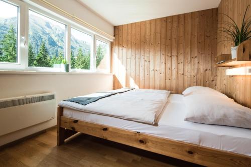 1 dormitorio con 1 cama con pared de madera en Hüttendorf Präbichl, en Vordernberg
