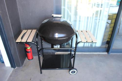 a grill sitting on a cart next to a bench at 365 Sunset Self Catering Apartments in Noordhoek