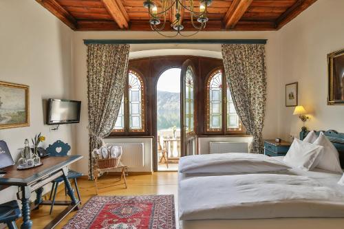 a bedroom with a bed and a desk and windows at Hotel See-Villa in Millstatt