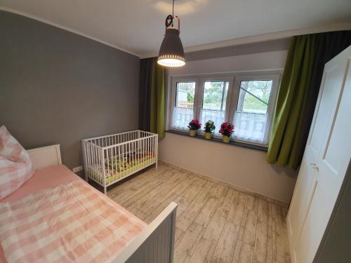 a bedroom with a crib and two windows at Ferienhaus Kaiserhof in Markkleeberg