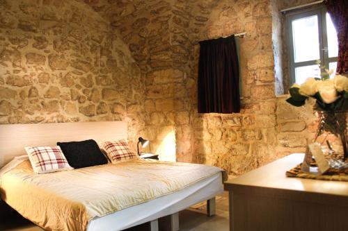 a bedroom with a bed in a stone wall at Al-Hakim Boutique Hotel Old Town Nazareth in Nazareth