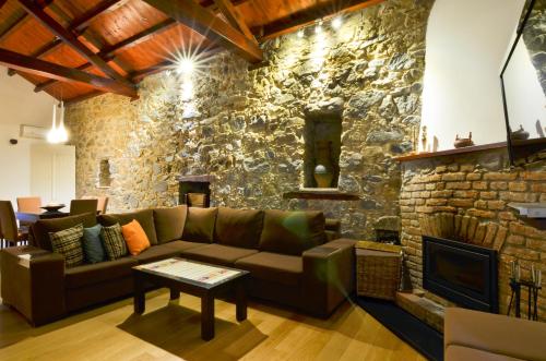 a living room with a couch and a stone wall at To Kastri in Kalopanayiotis