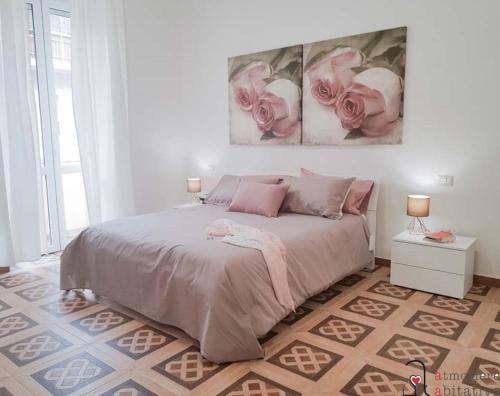 - une chambre avec un lit orné de 2 roses roses sur le mur dans l'établissement CASACRIZIA, à Cagliari