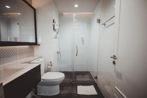 a white bathroom with a toilet and a shower at AVA Hotel in Phitsanulok