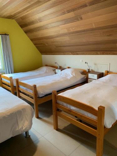 1 dormitorio con 3 camas y techo de madera en In den Jager, en Poperinge