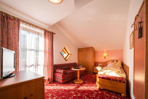 a bedroom with a bed and a couch and a window at Hotel Krimmlerfälle in Krimml