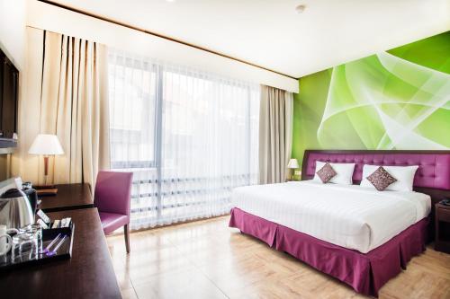 a bedroom with a large bed and a green wall at Kuta Central Park Hotel in Kuta