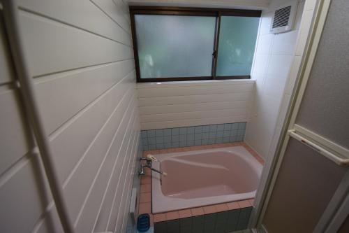 a bath tub in a bathroom with a window at Hanareya in Tsushima