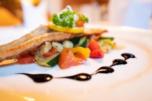 a plate of food with a sandwich and two spoons at Hotel Krimmlerfälle in Krimml