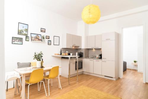 kuchnia i jadalnia ze stołem i żółtymi krzesłami w obiekcie Prater Balcony Suite w Wiedniu
