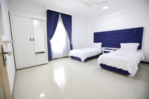 a hotel room with two beds and a window at Al Rayyan Hotel Apartments Muscat in Seeb
