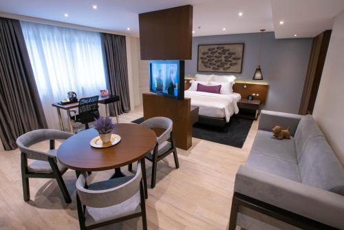 une chambre d'hôtel avec un canapé, une table et un lit dans l'établissement Coro Hotel, à Manille