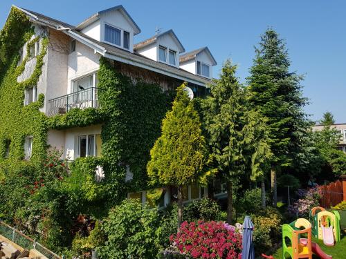 an ivycovered building with a garden in front of it at Dom Wypoczynkowy Anna in Kołobrzeg