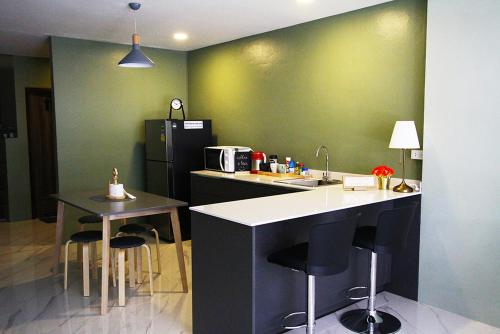 una cocina con paredes verdes y una barra con taburetes en 398 HOSTEL, en Bangkok