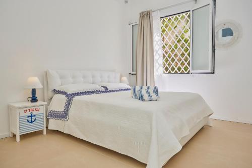a white bedroom with two beds and a window at CASA sugli SCOGLI in Fontane Bianche