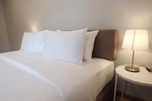 a bed with white pillows and a lamp on a table at Maleesa Place Hua Hin in Hua Hin