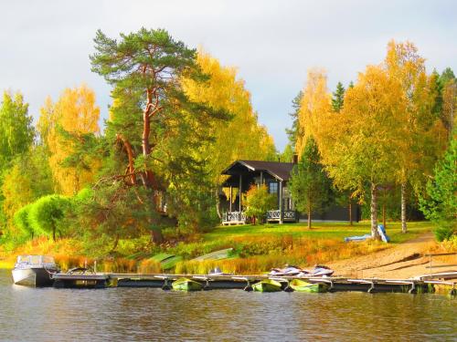 a house on the shore of a lake with boats in the water at Holiday Village Tahko-Tours in Tahkovuori